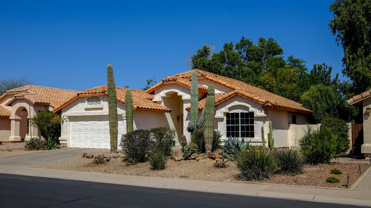 Tidy desert front yard with saguaro cacti beside a tile-roof Phoenix home