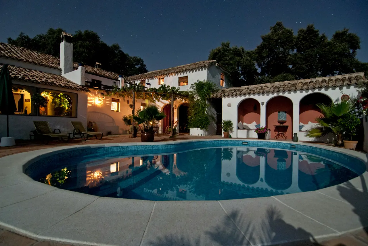 Twilight view of a Spanish-style home with a clean pool courtyard
